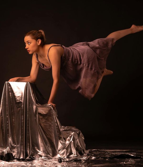 Athletic woman performing dynamic rhythmic movements in a dark studio.