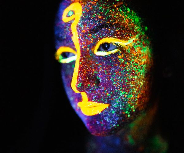 Man doing explosive cardio movement with glowing neon background.